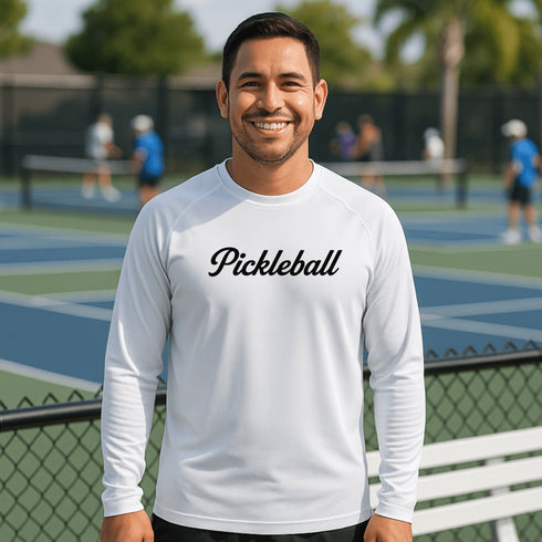 Man wearing a white 'Pickleball' shirt on a tennis court with other players in the background.